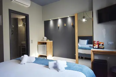 a hotel room with two beds and a television at Be My Guest Athens in Athens
