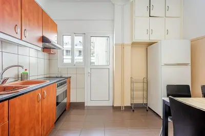 a kitchen with wooden cabinets and a sink and a refrigerator at Apartment in the Middle of Everything in Athens