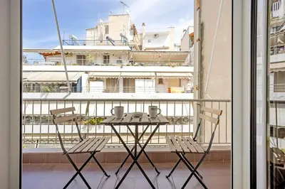 a balcony with a table and chairs and a large building at Apartment in the Middle of Everything in Athens