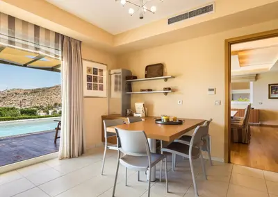 a dining room with a table and chairs and a large window at Analisa Luxury Villa in Sounio