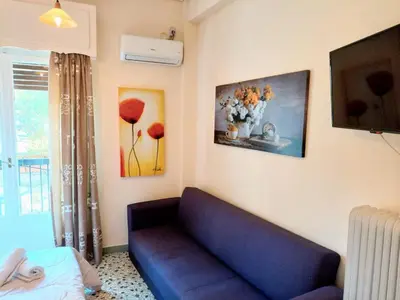 a living room with a blue couch and flowers on the wall at Cozy apartment in Acropolis with roof garden in Athens