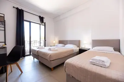 a hotel room with two beds and a balcony at Stone Palace Hotel Near Athen's Airport Free Shuttle From and to Athen's Airport in Spáta