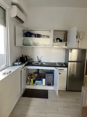 a kitchen with white cabinets and a stainless steel refrigerator at Holiday Apartment Glyfada in Athens