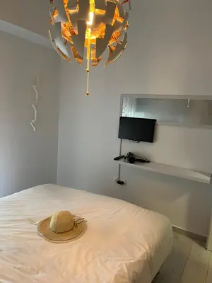 a hat on a bed in a room with a chandelier at Holiday Apartment Glyfada in Athens