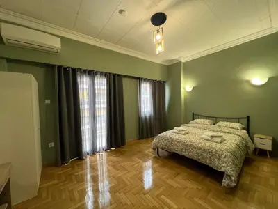 a bedroom with a bed with green walls and wooden floors at Sfiggos 54 Guest House in Athens