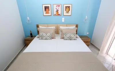 a blue bedroom with a large bed with pillows at Yiannis Studios in Agia Marina Aegina