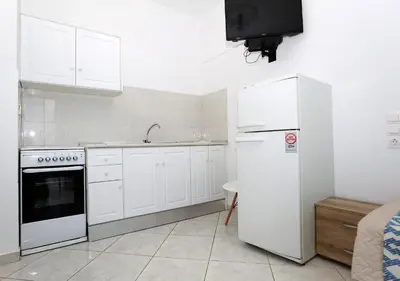 a kitchen with white cabinets and a white refrigerator at Yiannis Studios in Agia Marina Aegina