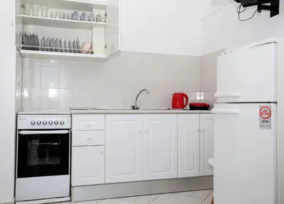 a kitchen with white cabinets and a white refrigerator at Yiannis Studios in Agia Marina Aegina