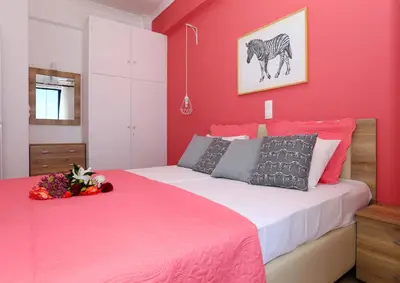a bedroom with a pink wall and a bed at Yiannis Studios in Agia Marina Aegina