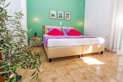 a bedroom with a bed with pink and purple pillows at Yiannis Studios in Agia Marina Aegina