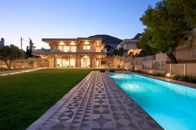 a house with a swimming pool in front of a yard at Elaia Luxury Suites Lagonisi in Lagonissi