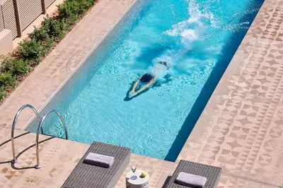 a man in a pool with a paddle in it at Elaia Luxury Suites Lagonisi in Lagonissi
