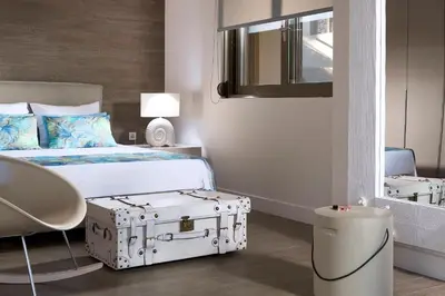a hotel room with a bed with a suitcase at Elaia Luxury Suites Lagonisi in Lagonissi