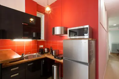 a kitchen with red walls and a refrigerator and a microwave at Under the shade of Acropolis by YHA in Athens