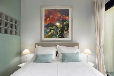 a bedroom with a white bed with a painting on the wall at Under the shade of Acropolis by YHA in Athens