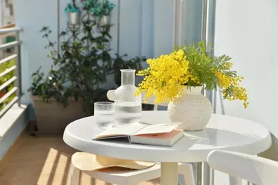 a white table with a vase of flowers and a book at Alekos Apartments 1 - Νetflix & Comfort in Athens