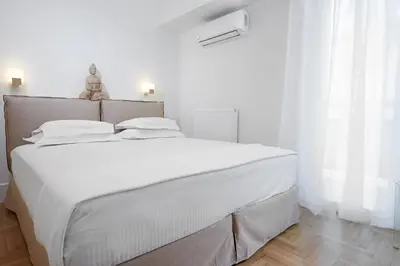 a white bedroom with a large bed with white sheets at Lux Central Apt at Kolonaki Area in Athens