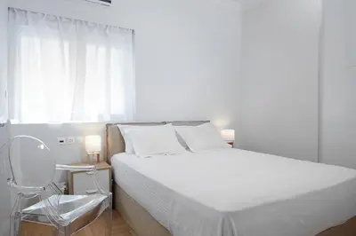 a white bedroom with a bed and a chair at Lux Central Apt at Kolonaki Area in Athens