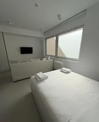 a white room with a bed and a large window at Euryclea Residences in Athens