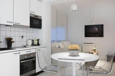 a white kitchen with a white table and chairs at Euryclea Residences in Athens