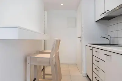 a white kitchen with a wooden chair in a kitchen at Euryclea Residences in Athens