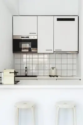 a kitchen with white cabinets and two stools at Euryclea Residences in Athens