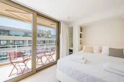 a bedroom with a bed and a balcony with chairs at The Room with a View in Athens
