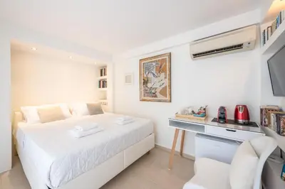 a white bedroom with a bed and a desk at The Room with a View in Athens