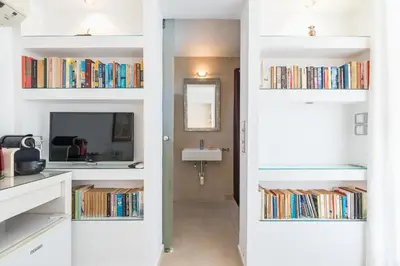 a room with white walls and shelves filled with books at The Room with a View in Athens