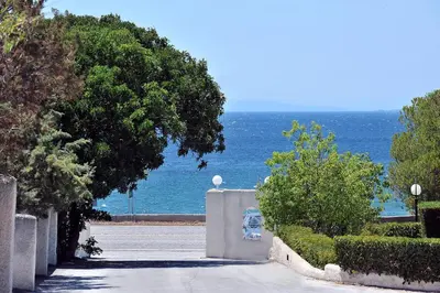 a car parked on a road next to the ocean at Sarwnisland in Lagonissi