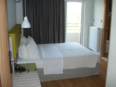 a bedroom with a bed with white sheets and a window at Elements Rooms & Apartments in Athens