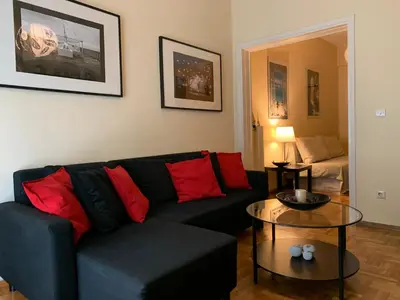 a living room with a black couch and red pillows at Renovated cozy apartment near to Acropolis in Athens