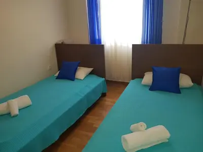 two beds in a room with blue sheets and blue pillows at Koukaki Apt 5 min walk to Acropolis in Athens