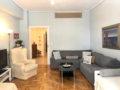 a living room with a gray couch and a table at Koukaki Apt 5 min walk to Acropolis in Athens