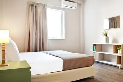 a white bedroom with a bed and a window at Athens Connection Apartments in Athens