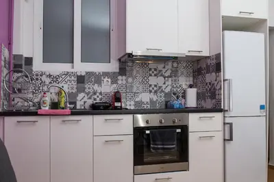 a kitchen with white cabinets and black and white tiles at Voula's Apartment in Athens