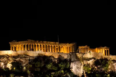 a building on top of a mountain at night at Acropolis Suite in Athens