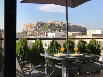 a table with two drinks and an umbrella on a balcony at Acropolis Suite in Athens