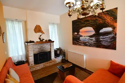 a living room with a fireplace and orange furniture at Villa Filoxenia all seasons, near airport, sea, Athens in Aghia Marina