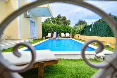 a swimming pool seen through a chain link fence at Villa Filoxenia all seasons, near airport, sea, Athens in Aghia Marina