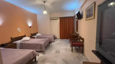 a room with three beds and a flat screen tv at Hotel Cosmos in Athens