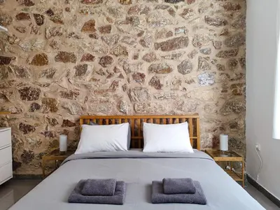 a bedroom with a stone wall and a bed with two towels at KYMA Apartments - Athens Acropolis 2 in Athens
