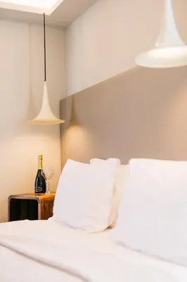 a bed with white sheets and a bottle of wine on a table at 360Degrees Pop Art Hotel in Athens