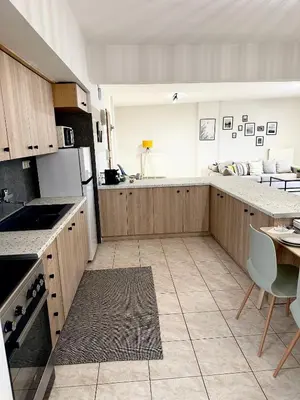 a kitchen with wooden cabinets and a table in it at Anastasias house near Athens airport in Spáta