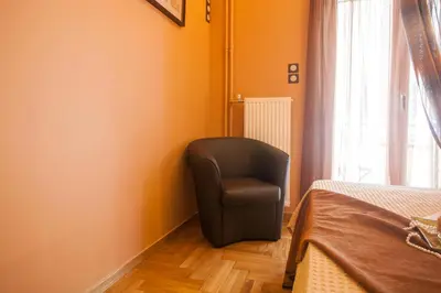 a black chair sitting in a room with a window at Elegant and Safe Gold and Blue Apartment walk to Acropolis in Athens