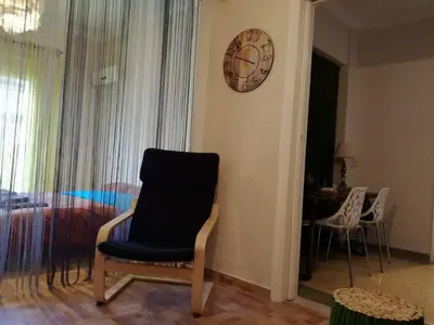 a room with a chair and a clock on a wall at Biophylic - 3bdr apartment in Athens