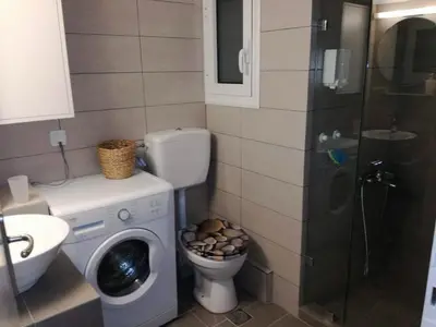 a bathroom with a washing machine and a toilet at Biophylic - 3bdr apartment in Athens