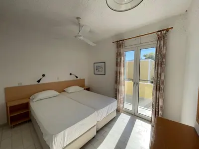 a bedroom with a bed and a large window at Esperides Maisonettes in Agia Marina Aegina