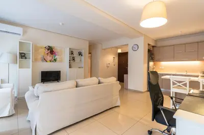 a living room with a white couch and a kitchen at Patissia Apartment in Athens
