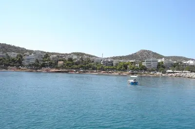 a small boat in the water near a beach at Starapartment Athens-Varkiza Top 1 in Varkiza